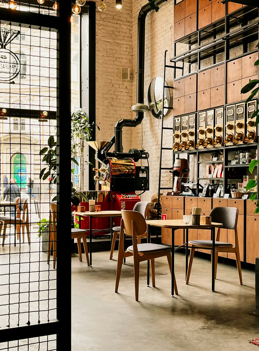 Interior do café, com mesas de madeira e prateleiras de café em grão