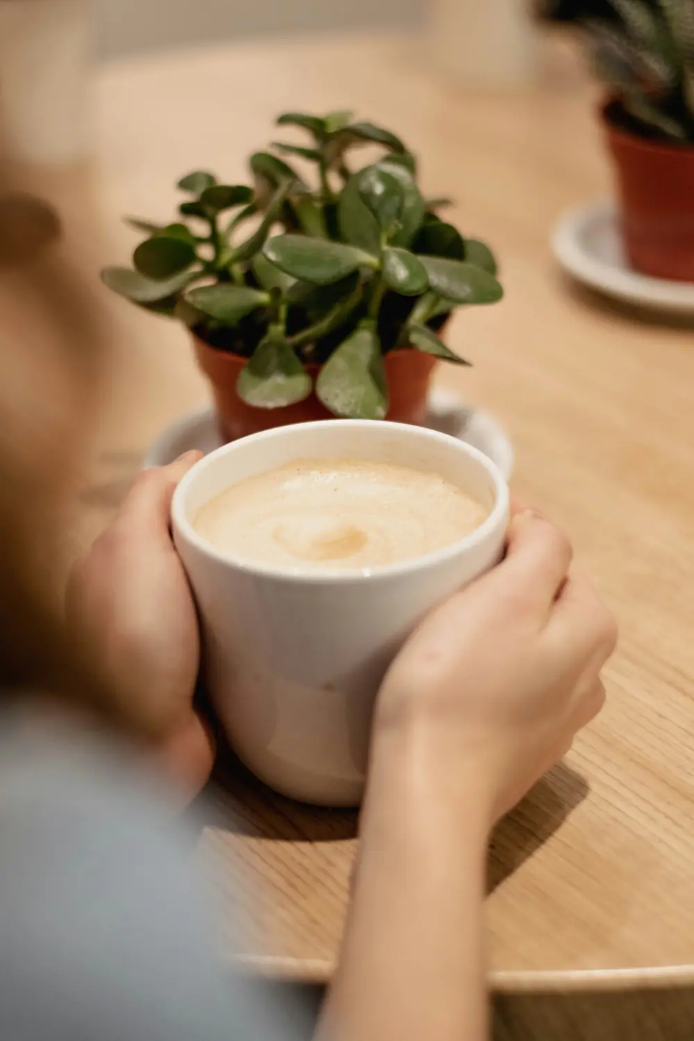 Mãos a segurar uma chávena de café com leite